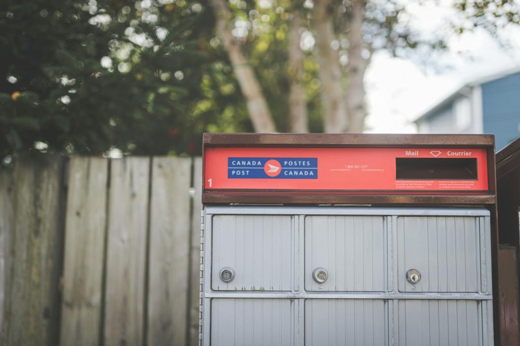 Close-up image of a Canada Post mailbox outdoors with natural background.