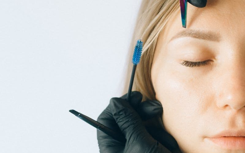 Close-up of a woman receiving professional eyebrow and lash treatment in a beauty salon.