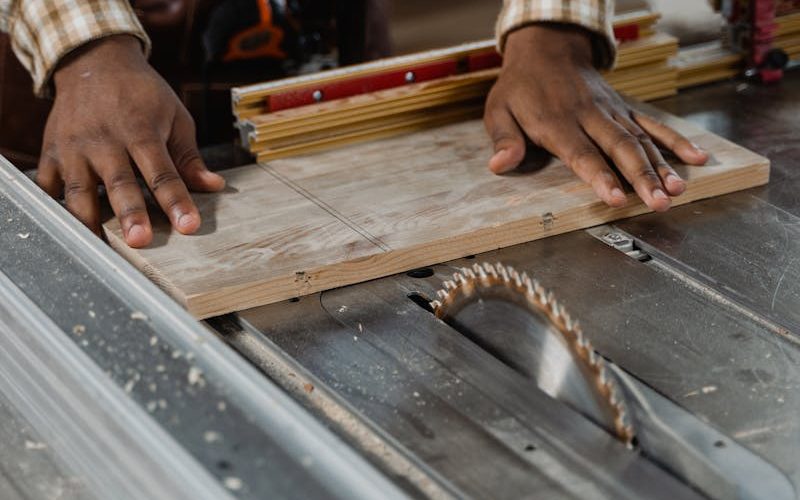 Carpenter working with precision on a table saw in a workshop, showcasing woodworking skills.