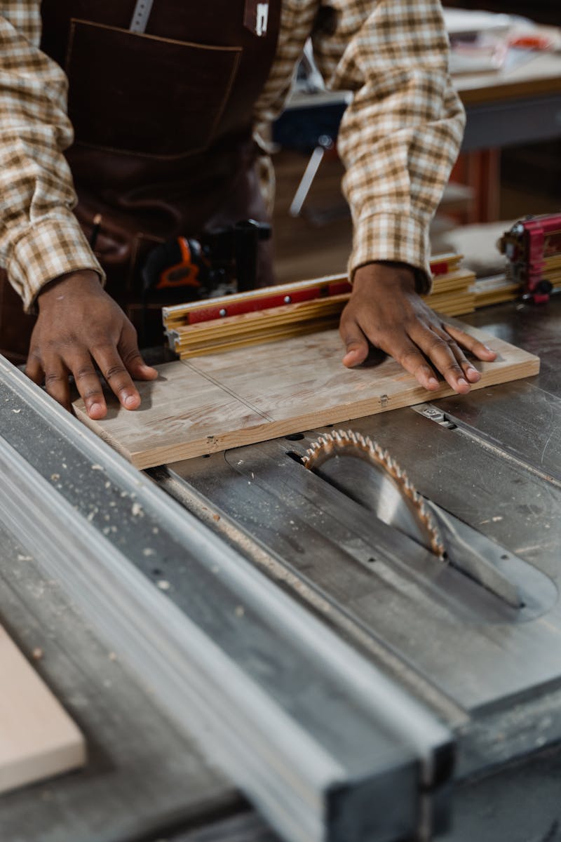Carpenter working with precision on a table saw in a workshop, showcasing woodworking skills.
